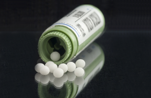 frasco e glóbulos de cor branca utilizados na medicina homeopática